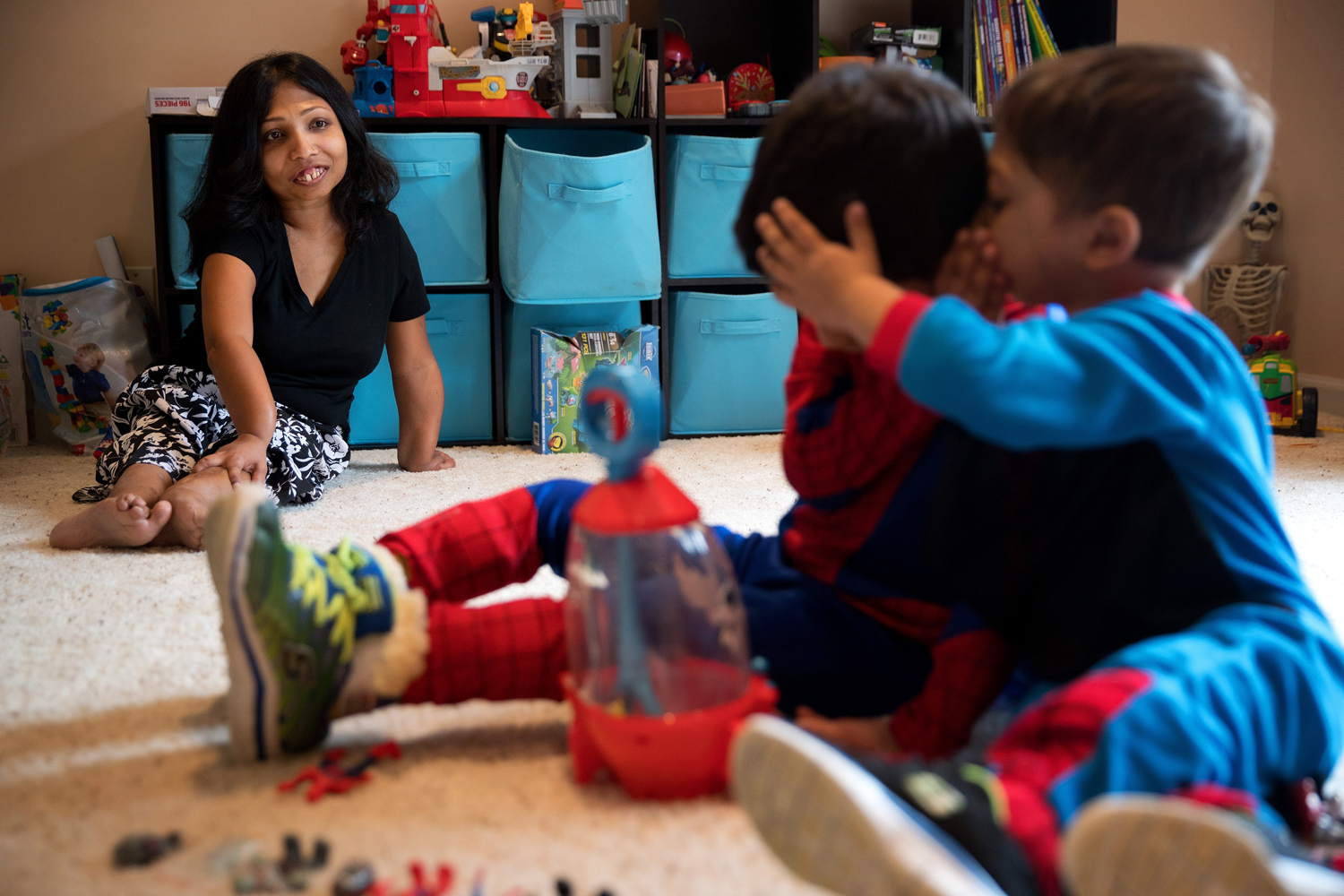 Neena Nizar, whose Jansen's went undiagnosed in her own childhood in the United Arab Emirates, watches her sons whisper to each other while playing a game with superhero figures in March at their Elkhorn home.