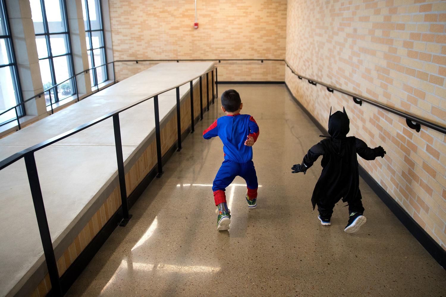 Dressed as superheroes, Arshaan, left, and Jahan play in the hallway at the Omaha Conservatory of Music before their piano lessons in January.